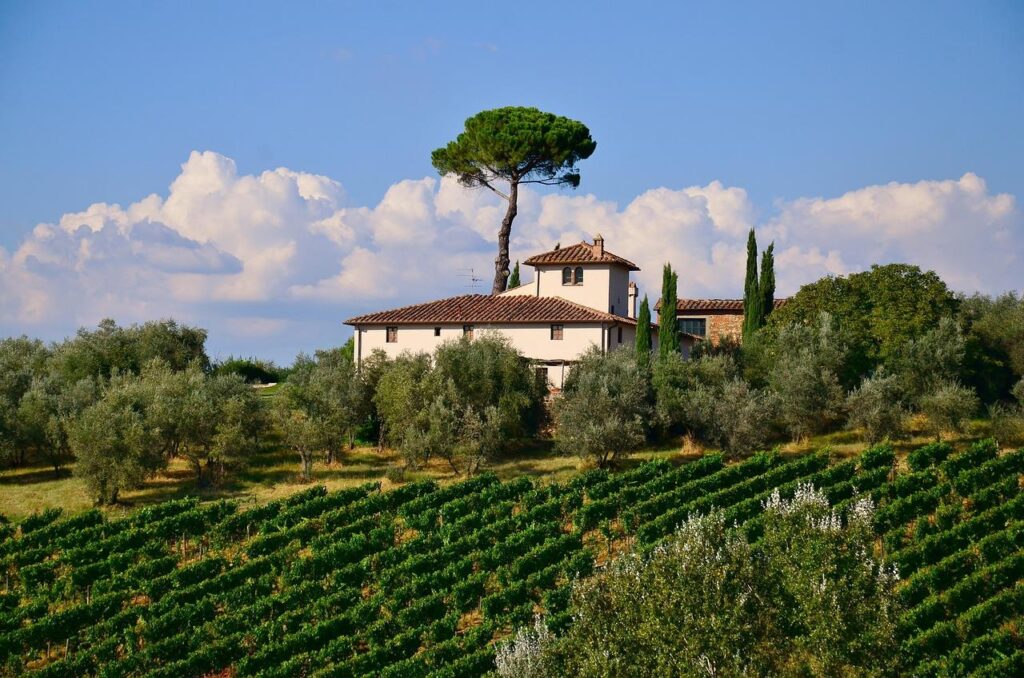 Luchtfoto van Toscaanse villa met zwembad omgeven door wijngaarden en cipressenlanen in Chianti-regio